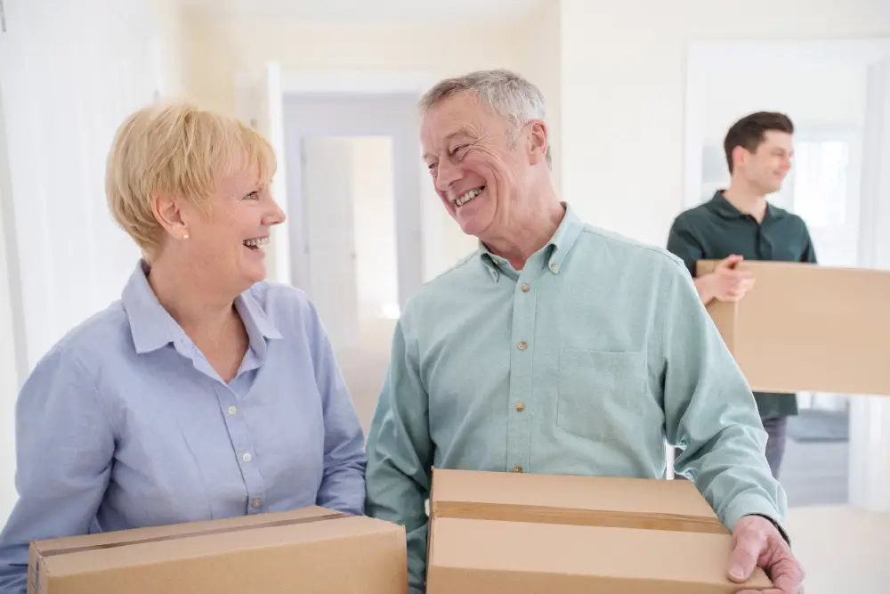a senior couple carrying moving boxes