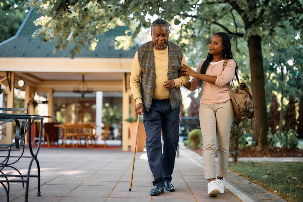 Adult daughter walking with senior man outside 