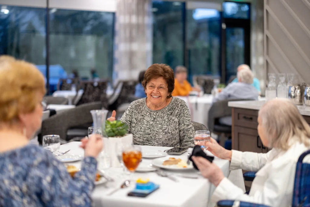 Three elderly women dining at Clarendale Arcadia while discussing what redefining ready looks like through their senior ambassador program in Phoenix, AZ.