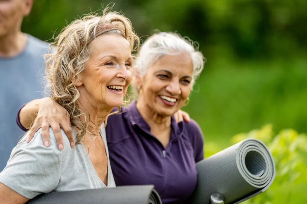 2 female seniors with holding yoga mats after their yoga class. One of the best Independent Living activities for seniors in Phoenix, AZ, at Clarendale Arcadia.
