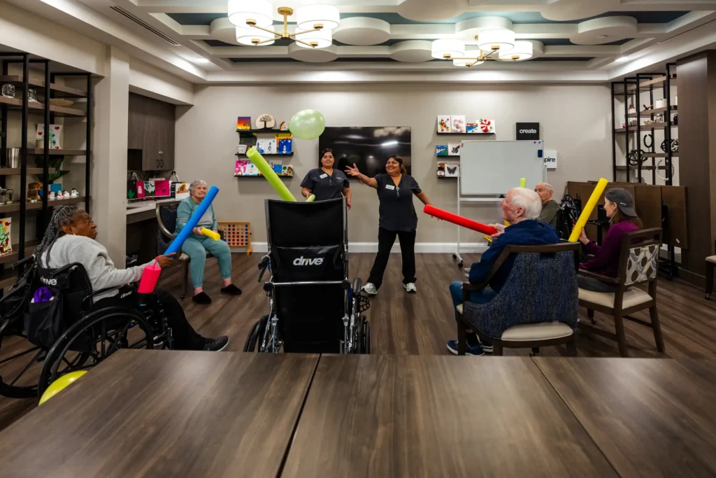Memory care residents of Clarendale Arcadia in Phoenix, AZ, playing with pool noodles, a great exercise to help a parent with dementia. 