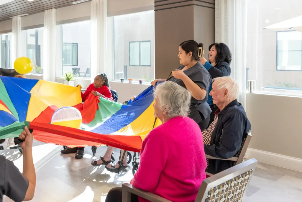 Residents of Clarendale Arcadia in memory care, playing parachute ball a great exercise to help parents with dementia
